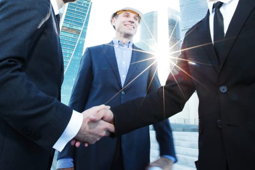 Investor and contractor shaking hands, view from below