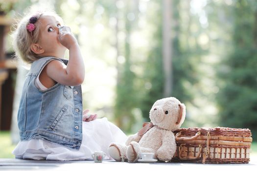 Pretty girl playing with teddy bear outdoors