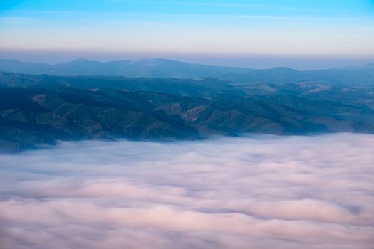 Autumn landscape view of mountain hills above misty clouds at sunrise, High Tatras, Slovakia