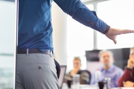 Business man making a presentation at office. Business executive delivering a presentation to his colleagues during meeting or in-house business training. Rear view. Business and entrepreneurship.