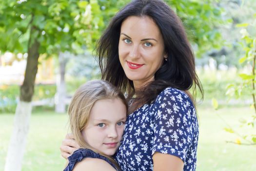 Embracing mother and daughter in summer on green background