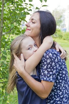 Embracing mother and daughter in summer on green background