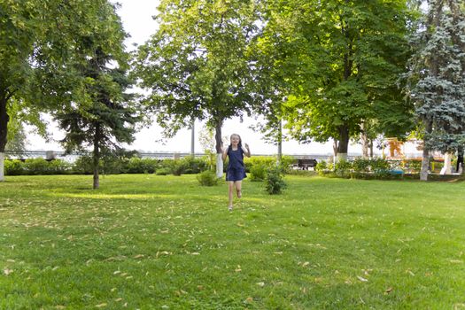 Girl is running in park on green grass