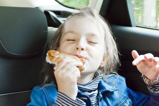 Eating cute girl with blond wet hair sitting inside car