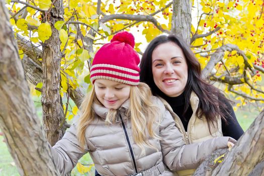 Photo of mother and daughter on spreading tree in autumn