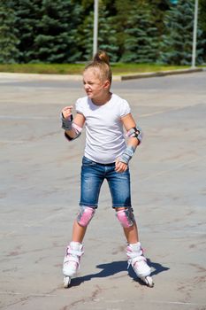 Learning girl on roller skates in summer