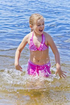 Jumping girl in pink swimsuit with droplets of water