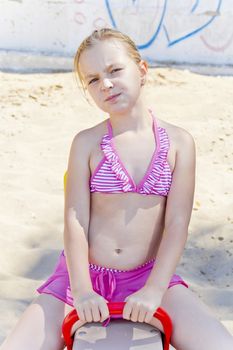 Chewing girl at playground on the beach