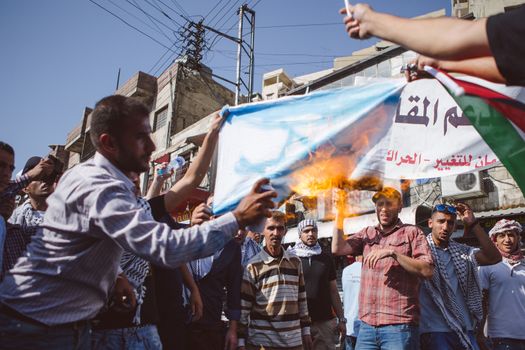 JORDAN, Ammam : A man burns an Israeli flag while around 5,000 people protest against Israeli violations against Palestinians  in the center of Ammam, capital city in Jordan on October 16, 2015. Demonstrators ask for the end of 1994 Israel-Palestine peace treaty. Since October 1st, 2015, tensions in border between Israel and the Gaza strip get higher. Seven Israelis have been killed in more than two dozen attacks by Palestinians this month, mostly in Jerusalem, and about 70 have been wounded. 