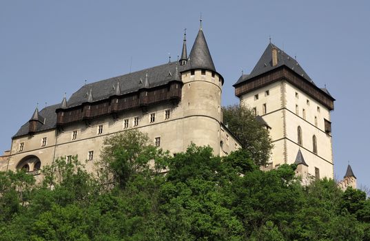 Karlstejn Castle - gateway and watch tower. Karlstejn Castle - is a famous Gothic castle founded 1348 by Charles IV - King of Bohemia. The castle served as a place for safekeeping the Imperial Regalia as well as the Bohemian coronation jewels, holy relics and other royal treasures. Located about 30 km southwest of Prague above the village named Karlstejn, it is one of the most famous and most frequently visited castles in the Czech Republic. The castle was founded in 1348 by Charles IV.