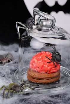 Biscuits with marzipan in the form of the brain under a glass bell and spiders