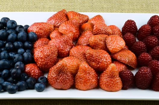 Strawberry, raspberry, blueberry fruits on white plate
