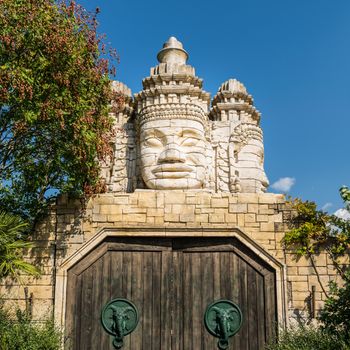 Stone faces of a temple and wooden portal with door knocker shaped like elephant's head.