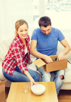 repair, building and home concept - smiling couple unpacking kitchenware