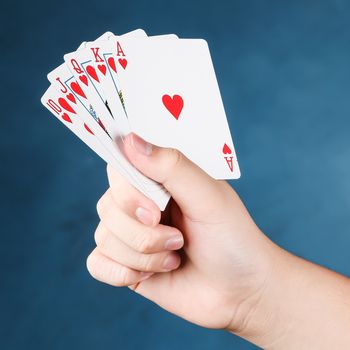 A royal straight flush playing cards poker in hand in hearts