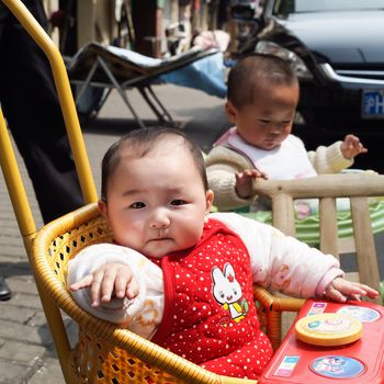 SHANGHAI, CHINA - April 9, 2011 :  Chinese cute girl kid with baby carriage in the market