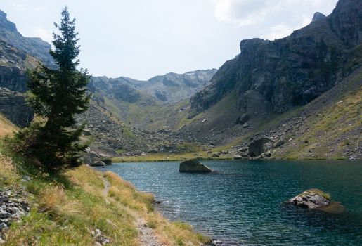 Hiking in summer Alps to blue lake of mountain
