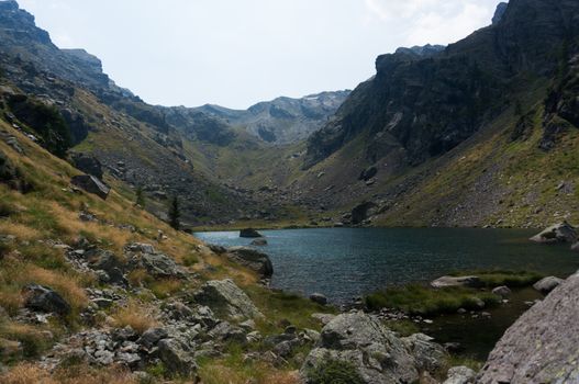 Hiking in summer Alps to blue lake of mountain