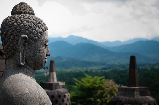 Stone budhha sideview in front of two stupas at Borobudur near Yogyakarta in Indonesia.