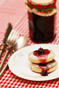 Curd sprinkled with powdered sugar and cherry jam
