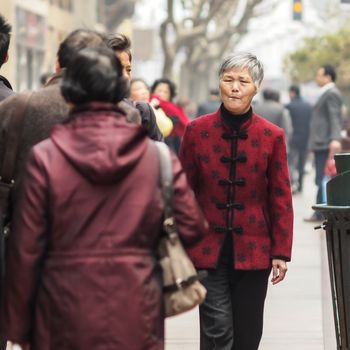 SHIANGHAI, CHINA - April 8, 2011 : Old Chinese woman with red traditional shirt walking at walk street in Shianghai.