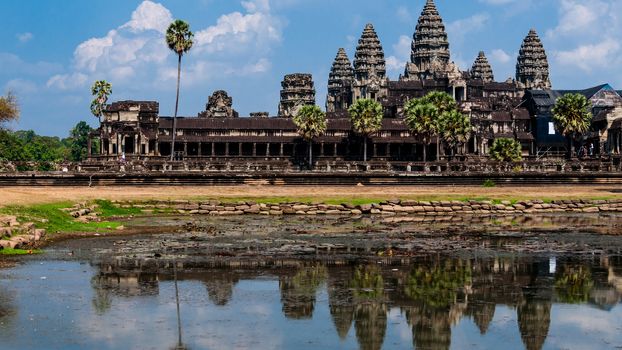 Front of Angkor Wat with reflection in water and a blue sky above