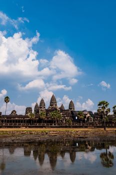 Front of Angkor Wat with reflection in water and a blue sky above