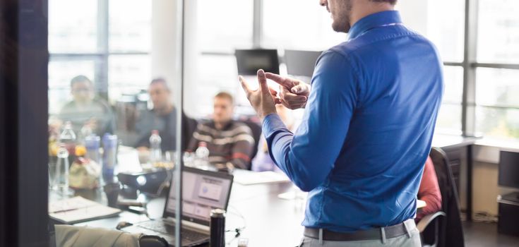 Business man making a presentation at office. Business executive delivering a presentation to his colleagues during meeting or in-house business training, explaining business plans to his employees.