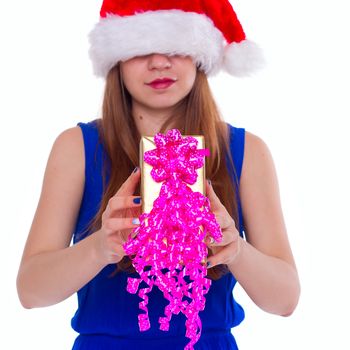 Young happy girl in Christmas hat. Standing indoors and holding huge christmas gift. isolate