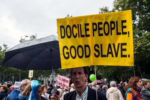 SPAIN, Madrid: A man with a poster reading Docile people, good slave attends a protest against the Transatlantic Trade and Investment Partnership in Madrid, Spain on October 17, 2015. Leaders are still reaching an agreement on the TTIP, a deal designed to boost the US economy and European Union by removing tariffs and other barriers to trade and foreign investment. Protesters argue the TTIP will support corporations at the expense of citizens, increase poverty and inequality and harm the environment. 