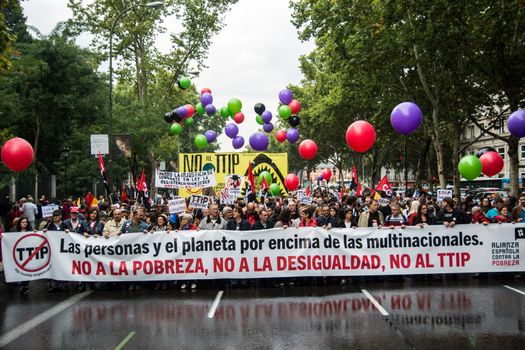 SPAIN, Madrid: Hundreds attend a protest against the Transatlantic Trade and Investment Partnership in Madrid, Spain on October 17, 2015. Leaders are still reaching an agreement on the TTIP, a deal designed to boost the US economy and European Union by removing tariffs and other barriers to trade and foreign investment. Protesters argue the TTIP will support corporations at the expense of citizens, increase poverty and inequality and harm the environment. 