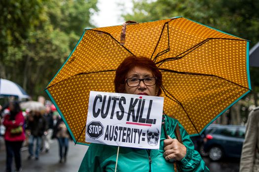 SPAIN, Madrid: A woman with an anti-austerity poster attends a protest against the Transatlantic Trade and Investment Partnership in Madrid, Spain on October 17, 2015. Leaders are still reaching an agreement on the TTIP, a deal designed to boost the US economy and European Union by removing tariffs and other barriers to trade and foreign investment. Protesters argue the TTIP will support corporations at the expense of citizens, increase poverty and inequality and harm the environment. 