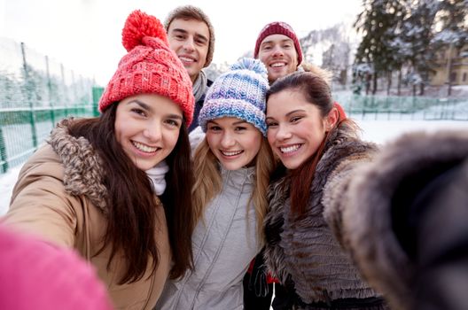 people, friendship, technology, winter and leisure concept - happy friends taking selfie with smartphone or camera outdoors