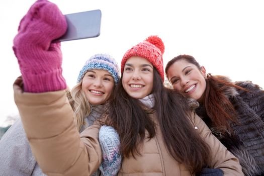 people, friendship, technology, winter and leisure concept - happy teenage girls taking selfie with smartphone outdoors