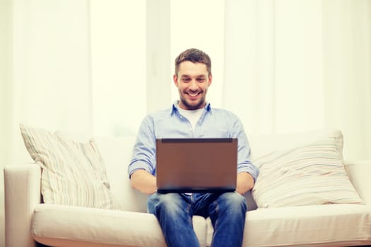 technology, internet and lifestyle concept - smiling man working with laptop at home