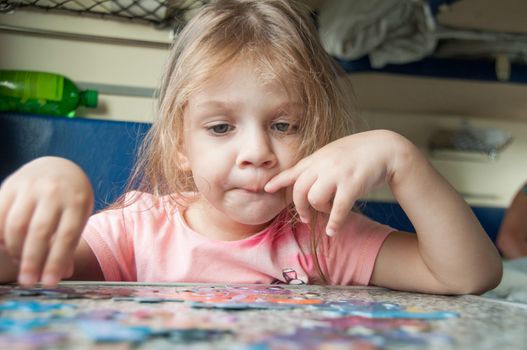 The three-year girl enthusiastically collects puzzles reserved seats at a table in a train