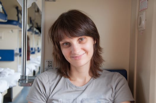 Young beautiful girl sits on the positive side of the bed in the second-class train carriage