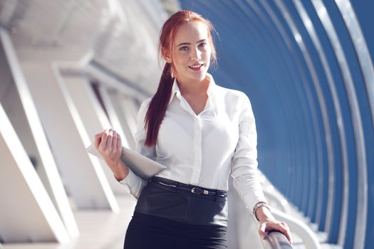 Beautiful modern businesswoman holding tablet computer inside modern building