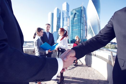 Business handshake, the deal Is finalized by group of people outside