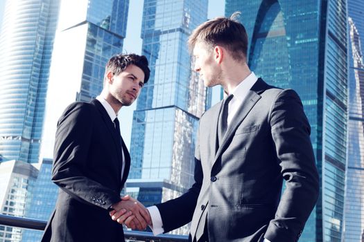 Business people shaking hands on skyscraper background