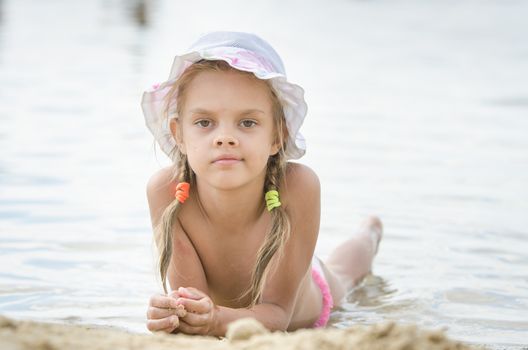 Six year old girl Europeans in panama lying on his stomach on the river bank