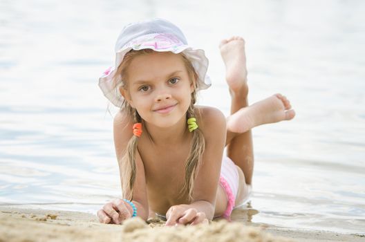 Six year old girl Europeans in panama lying on his stomach on the sand by the river