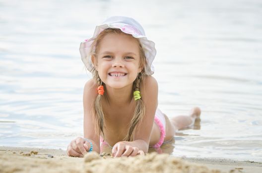Six year old girl Europeans in panama lying on his stomach on the sand by the river