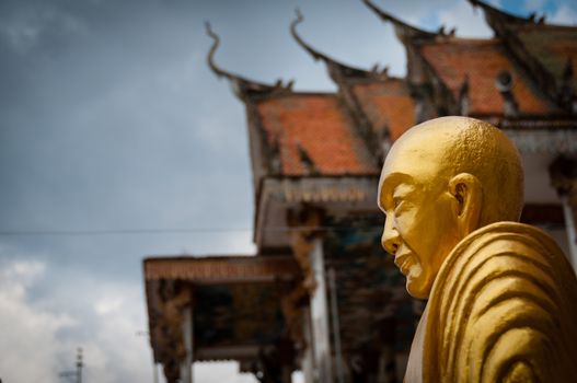 Golden Buddha with beautiful ancient temple in Laos under a cloudy but blue sky