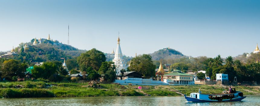 Boat on Irrawaddy river with Pagoda and village close to Mandalay Burma Myanmar