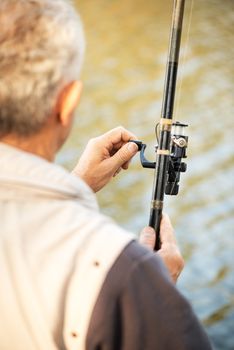 Senior Fisherman holding Fishing Rod with Reel.