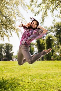 Happy young woman jumping in park and having fun.