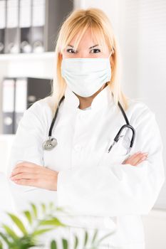 Portrait of female doctor with stethoscope and surgical mask standing in her office.