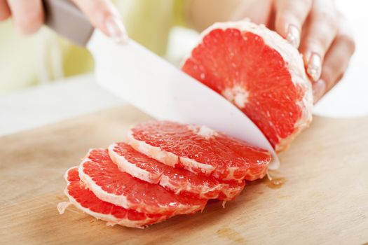 Female hands Cutting Grapefruit in the kitchen. Close-up. Selective Focus.