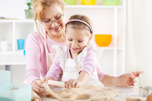 Beautiful happy grandmother and granddaughter a rolling pin together in the Kitchen. 